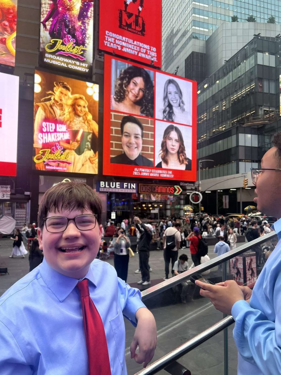 Carson Chesnut poses with his billboard in Time Square, Summer 2025. Photo provided by KPA. 