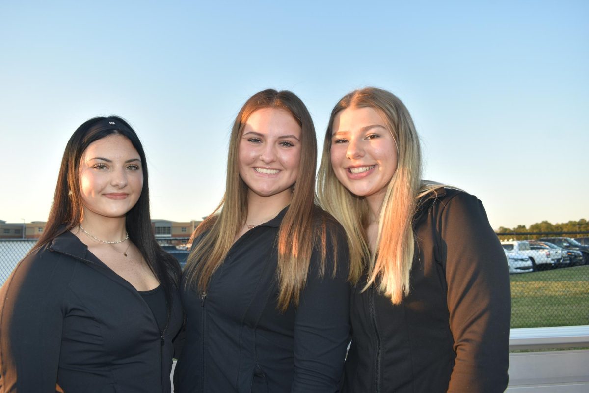 Grace Roberts (10), Abby Roberts (11), and Annie Pirtle (11) smile at the homecoming football game. The theme was "blackout." 